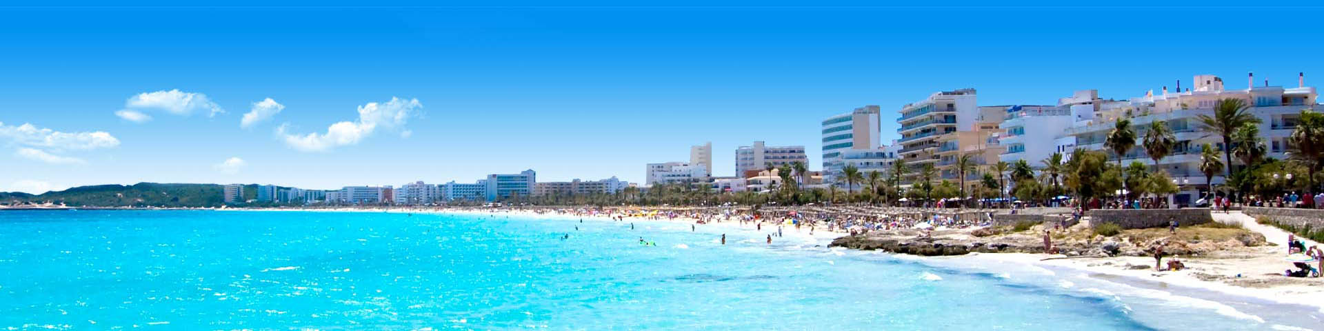 Uitzicht op toeristisch strand bij Cala Millor op Mallorca met de stad op de achtergrond