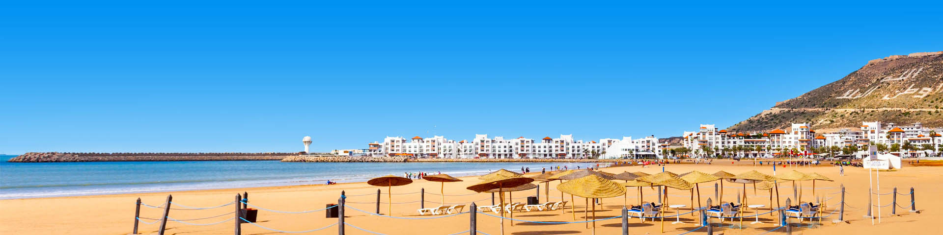 Goud zandstrand met ligbedden en parasols en gebouwen op de achtergrond