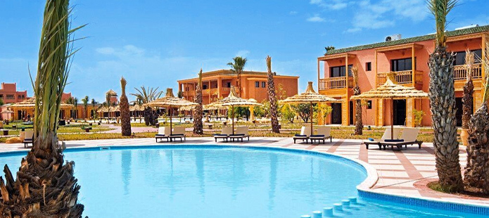 Een zwembad en ligbedden met parasols in een all in hotel