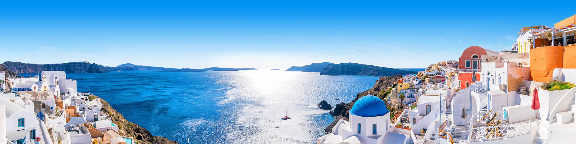 Witte en gekleurde huisjes in Santorini met een open blauwe zee 