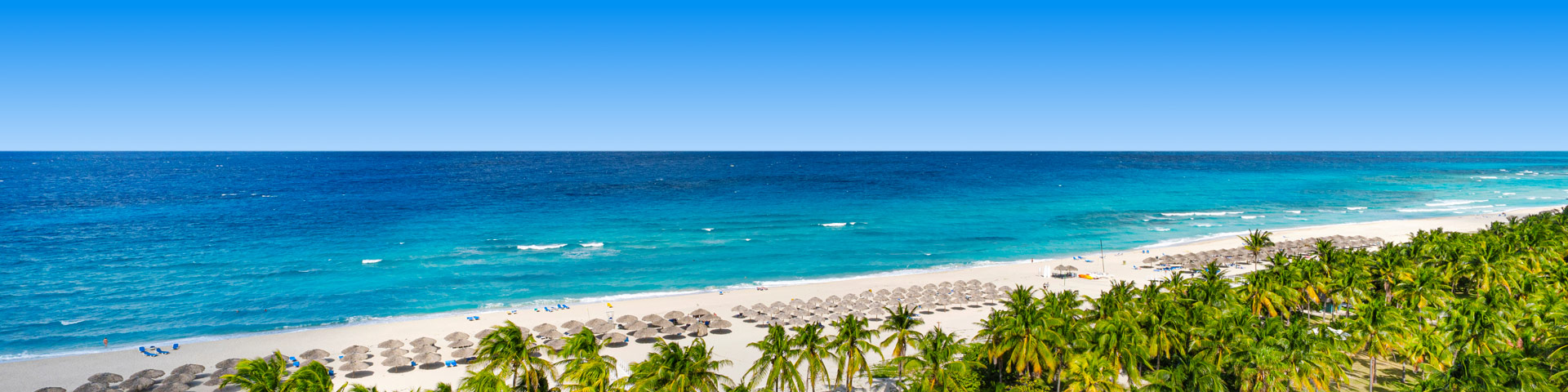 Zee met wit strand, parasols en palmbomen bij Varadero