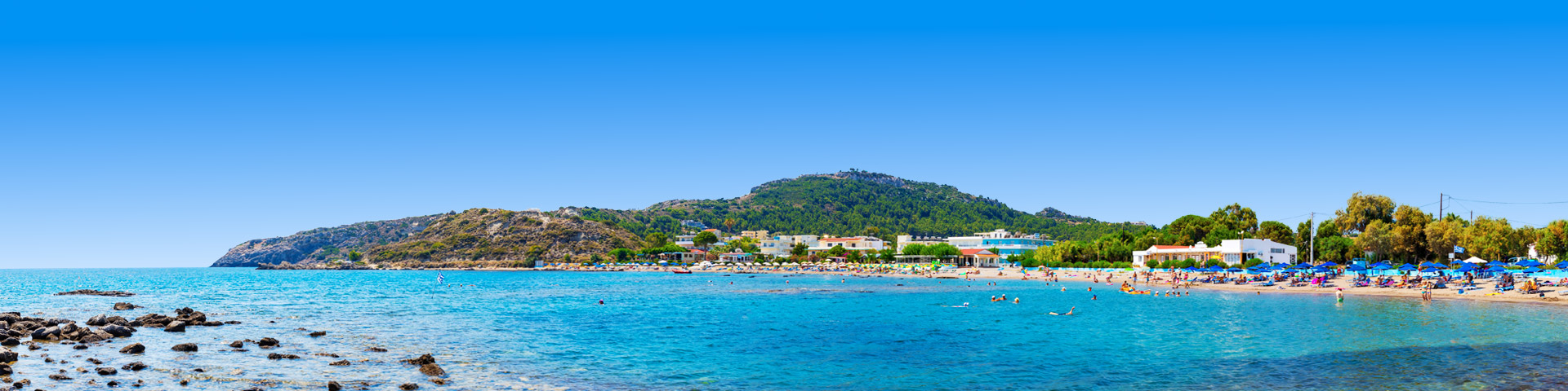 Zee en strand met parasols en heuvel bij Faliraki