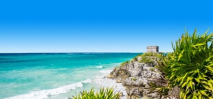 Uitzicht op een rotspartij aan het helderblauwe strand van Tulum in Mexico