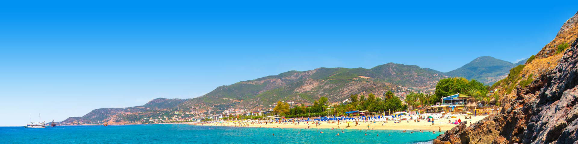 Strand met blauw water en bergen op de achtergrond