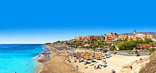 Het zandstrand en parasols op Tenerife