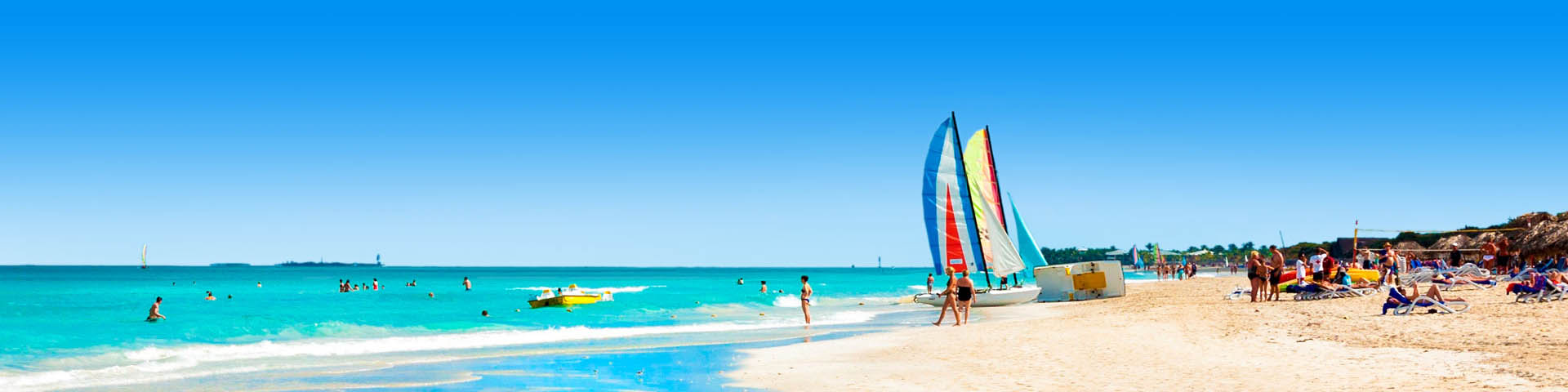 Wit zandstrand met azuurblauwe zee en vakantiegangers op het strand. 