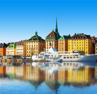 Boten dobberen voor kleurrijke gebouwen in Stockholm, Zweden onder een heldere blauwe lucht.