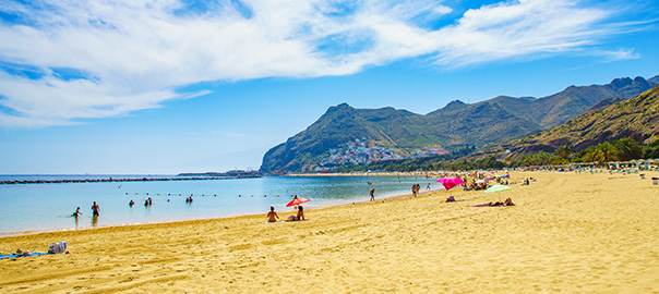 Geel zandstrand met bergen en de zee