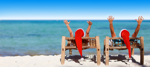 Twee vakantiegangers op het strand met kerstmutsen op